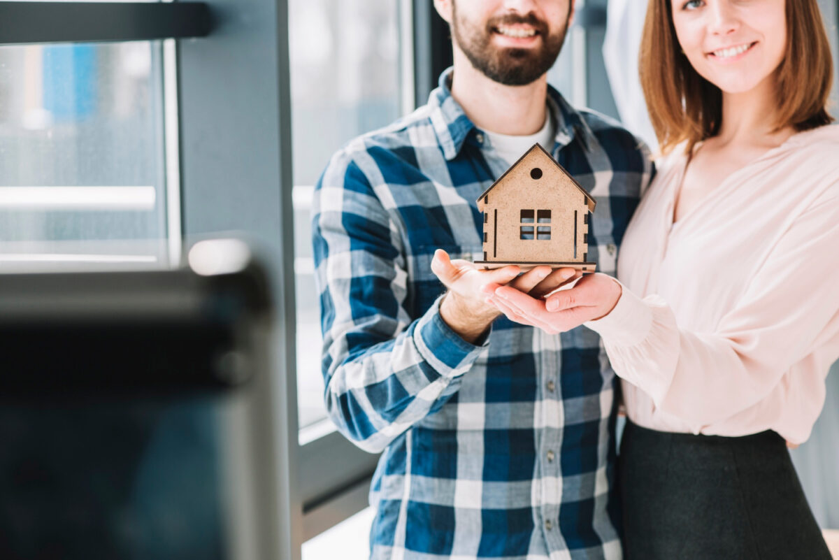 Un couple montre une maison en bois illustrant le concept d'achat immobilier